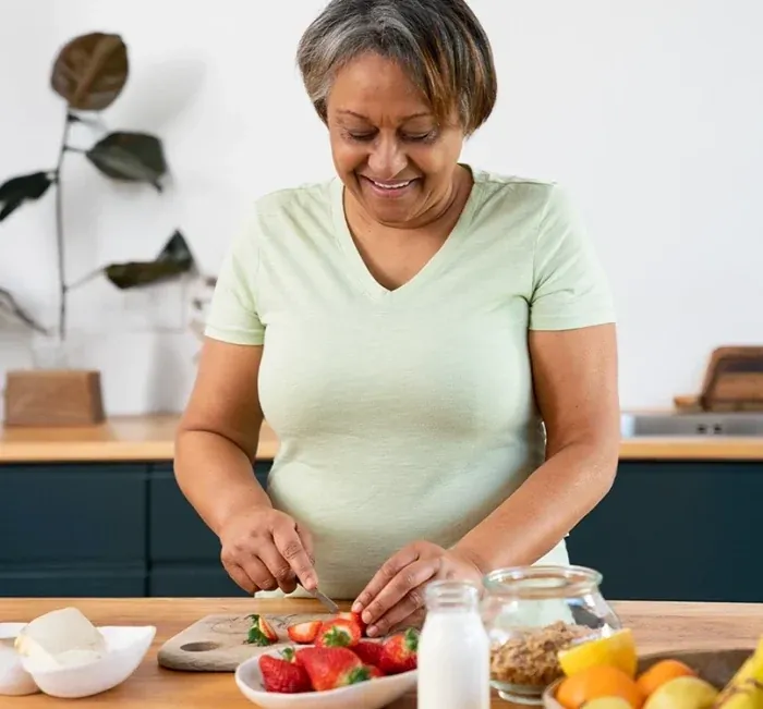 Woman slicing strawberries and fruit on a kitchen counter