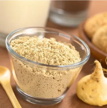 Maca root powder in a glass bowl with whole maca roots