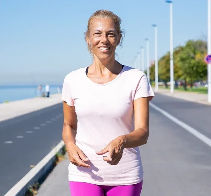 Woman in a pink top walking along a seaside path